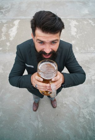 Téléchargez les photos : Fou drôle homme élégant boire de la bière. Heureux brasseur tenant verre avec de la bière. Longueur totale, grand angle - en image libre de droit