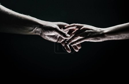 Zwei Hände strecken einander, schwarzer Hintergrund. Verliebtes Paar, das hads hält, aus nächster Nähe. Helfende Hand, Unterstützung, Freundschaft