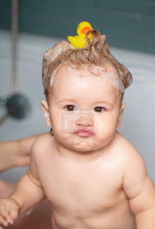 Téléchargez les photos : Il se baigne dans la salle de bain. Douche de bébé drôle. Portrait d'enfant amusant se baignant dans un bain avec de la mousse - en image libre de droit