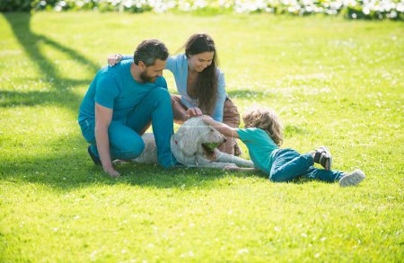 Téléchargez les photos : Portrait d'une famille souriante heureuse avec chien de compagnie relaxant dans le parc - en image libre de droit