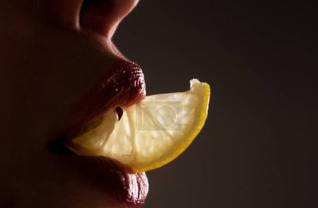 Foto de Labios de cerca con limones. Rebanada de limón en la boca. Cóctel de verano - Imagen libre de derechos