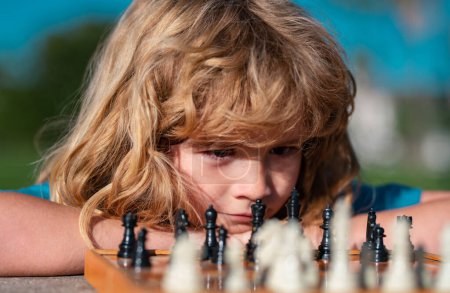 Téléchargez les photos : Pupil gamin penser à son prochain mouvement dans un jeu d'échecs. Intelligent intelligent enfants portrait gros plan - en image libre de droit