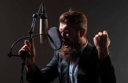Photo for Handsome man in recording studio gestures with hands. Music performance vocal. Singer singing song with a microphone - Royalty Free Image