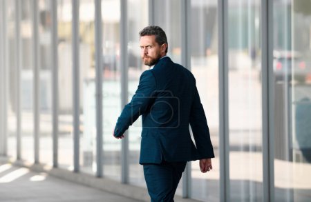 Téléchargez les photos : Homme d'affaires marchant devant le centre d'affaires. Portrait d'un jeune homme d'affaires confiant marchant dans la ville - en image libre de droit