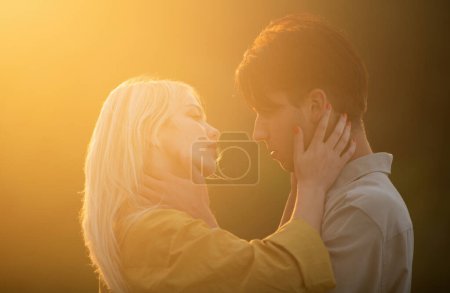 Téléchargez les photos : Embrasse un couple aimant au coucher du soleil. Un jeune couple amoureux se serre dans ses bras. Histoire d'amour - en image libre de droit
