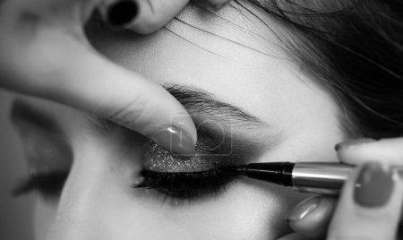 Foto de Retrato de cerca. Proceso de hacer maquillaje. Un maquillador profesional pinta modelos de pestañas en el estudio - Imagen libre de derechos