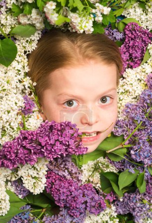 Photo for Funny little girl holding flowers in blooming summer garden. Teenager girl with bouquet of purple and white lilac - Royalty Free Image