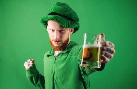Man on green background celebrate St Patricks Day. Portrait of excited man holding glass of beer on St Patricks day isolated on green