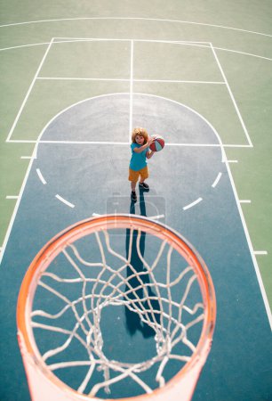 Téléchargez les photos : Vue d'angle du dessus de l'enfant id jouer au basket sur l'aire de jeux - en image libre de droit