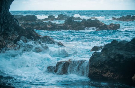 Téléchargez les photos : Des vagues éclaboussantes sur le rocher dans la mer. La vague a frappé la pierre dans l'océan avec un fond de tube d'eau - en image libre de droit