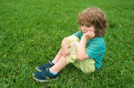 Foto de Es triste. Niño triste, siéntate en la hierba, verano. Infancia, juventud, crecimiento - Imagen libre de derechos