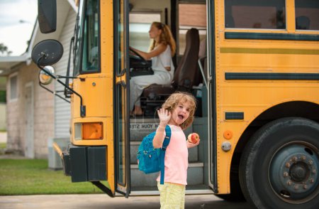 Foto de Lindos alumnos sonriendo a la cámara en el autobús escolar fuera de la escuela primaria. Regreso a la escuela y tiempo feliz - Imagen libre de derechos