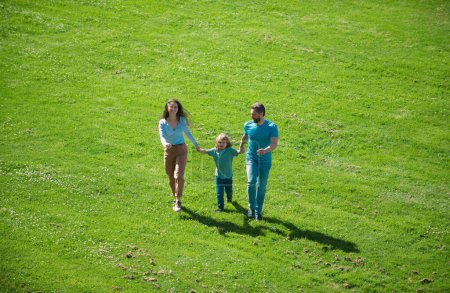 Téléchargez les photos : Bonne famille en promenade estivale. Père mère et enfant marchant dans le parc et profitant de la belle nature - en image libre de droit