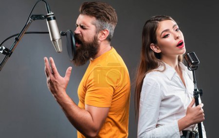 Photo for Singer duet couple is performing a song with a microphone while recording in a music studio - Royalty Free Image
