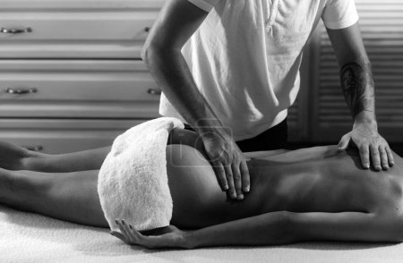 Foto de Masaje profesional en casa. Masaje de espalda. Terapia de masaje con fines de salud. Aceites de masaje y aceite corporal perfumado - Imagen libre de derechos