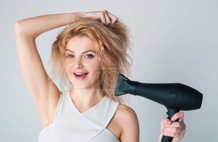 Photo for Health hair and beauty concept. Girl with blonde hair using hairdryer. Young attractive happy laughing blonde woman with hair dryer. Hairstyle, hairdressing concept - Royalty Free Image
