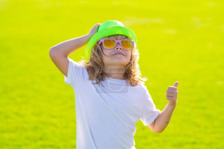 Téléchargez les photos : Enfants d'été en chapeau et lunettes de soleil. Portrait d'enfant à l'extérieur. Gros plan visage enfant jouant à l'extérieur dans un parc d'été - en image libre de droit
