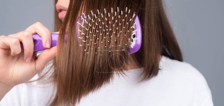 Téléchargez les photos : Fermer femme coiffeur avec peigne brossant les cheveux. Brunette femme peignage cheveux - en image libre de droit