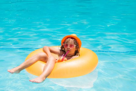 Téléchargez les photos : Enfant flottant dans la piscine. Enfant se relaxant dans la piscine, boire un cocktail d'été. Vacances d'été et vacances avec les enfants. Joyeux petit garçon jouant dans la piscine en plein air sur la chaude journée d'été - en image libre de droit