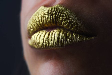 Téléchargez les photos : Fermez le visage de la femme avec des lèvres dorées. Peinture dorée sur la bouche. Des lèvres dorées. Maquillage de luxe lèvres dorées. Lèvres dorées avec rouge à lèvres métallique créatif. Lèvre en métal doré. Femme sensuelle bouche, gros plan, macro - en image libre de droit