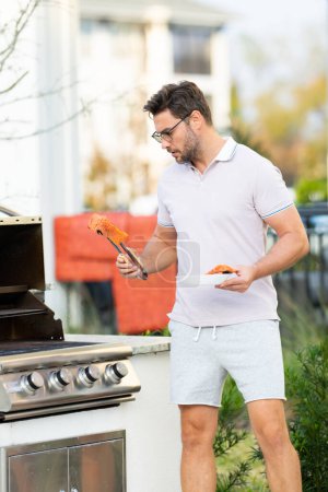 Photo for Cook man preparing barbecue grill outdoor. Man cooking tasty food on barbecue grill at backyard. Chef preparing food on barbecue. Millennial man grilling meat on grill. Bbq salmon fillet - Royalty Free Image