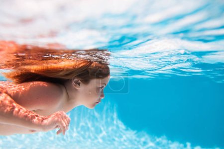 Téléchargez les photos : Vacances d'enfants et concept de vacances d'été. Enfant nageant sous l'eau dans la piscine. Des gosses drôles. Les enfants nagent dans l'eau de mer - en image libre de droit