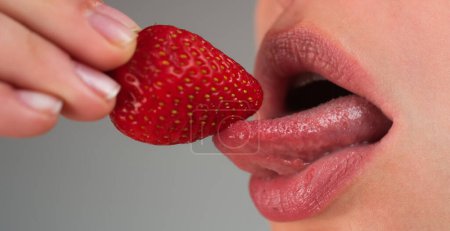 Foto de Mujer sexy comiendo fresa. Fresa en labios sensuales. Deseo. Sexy labios rojos con fresa. Macro primer plano de las mujeres lengua lamer fresas. Sexy fresa - Imagen libre de derechos