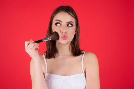 Woman applying foundation powder or blush with makeup brush. Facial treatment, perfect skin, natural make up, facial beauty. Isolated on studio background. Applying makeup