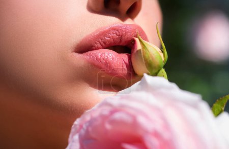 Foto de Labios sexys. Detalle de maquillaje de labios rojos belleza. Labios con flores primaverales de primer plano. Hermosos labios de mujer con rosa - Imagen libre de derechos