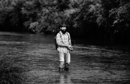 Foto de Hombre de pesca y relajarse mientras disfruta de hobby. Un pescador con caña de pescar en el río. Pescador y trucha. Manteniendo trucha marrón - Imagen libre de derechos
