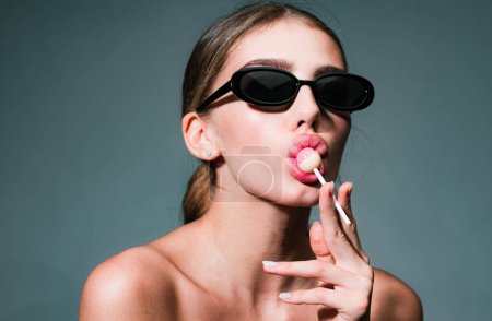 Photo for Sexy girl face. Sensual beautiful young woman lick lollipop on studio background. Beauty, fashion. Cosmetics, make-up - Royalty Free Image