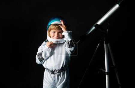 Photo for Child boy with a telescope imagines himself to be an astronaut in an space helmet. Astronomy and astrology concept - Royalty Free Image