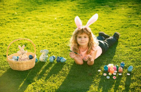 Photo for Child boy with easter eggs and bunny ears laying on grass. Easter kids with bunny ears and on grass background - Royalty Free Image