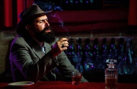 Portrait of a handsome bearded man, with a glass of alcohol in his hands. Rest and relaxation