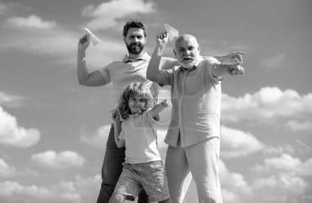 Photo for Active family leisure with kids. Boy son with father and grandfather with a toy airplane plays on summer sky background. Family adventure, imagination, innovation and inspiration - Royalty Free Image