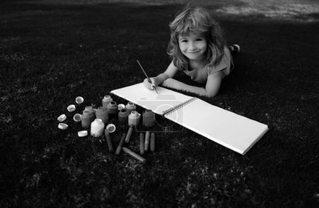 Téléchargez les photos : Peinture pour enfants avec peinture couleur et pinceau dans le parc en plein air. Joyeux enfant jouant dehors. Dessin thème d'été. Imagination concept enfants - en image libre de droit