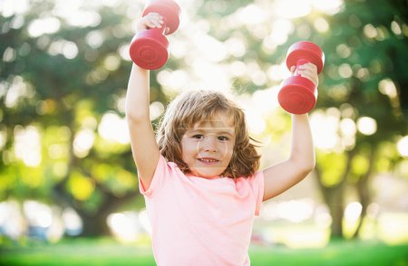 Photo for Happy boy workout with dumbbell in park. Sporty activity. Kid sport. Child exercising outdoor - Royalty Free Image