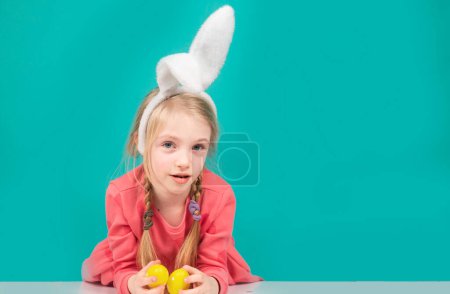 Foto de Niña con huevos de Pascua, concepto festivo de primavera. Niño sorprendido en orejas de conejo en vacaciones - Imagen libre de derechos