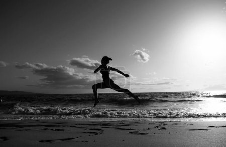 Téléchargez les photos : Femme courant sur la plage. Femme en bonne santé courir en mer, fille faire du sport en plein air, exercice féminin heureux, concept de remise en forme et de soins de santé sur fond naturel - en image libre de droit
