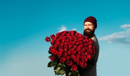 Foto de Hombre con ramo de flores. Feliz hombre sostiene un gran ramo de rosas rojas, proponer a novio en la fecha - Imagen libre de derechos