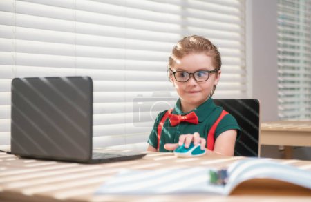 Photo for Smart school boy at home writing homework. Little student with notebook computer ready to study. School remote, online learning. Kid at home class learning - Royalty Free Image