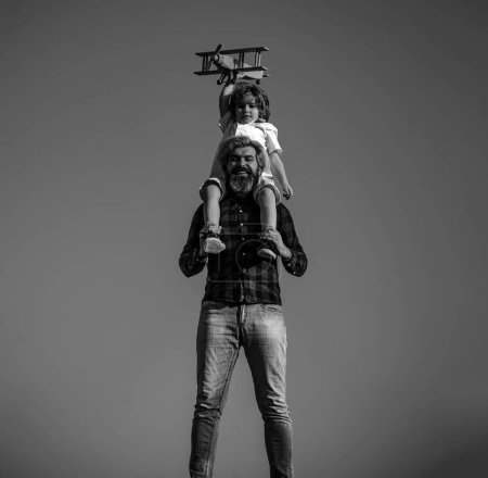 Foto de Padre e hijo jugando con un avión de madera. Niño sentado en los hombros de los padres - Imagen libre de derechos