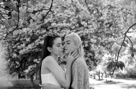 Foto de Chicas de primavera. Una pareja de lesbianas besándose. Hermosa chica sexy primavera con flores de sakura. Un beso sensual. novias amor - Imagen libre de derechos