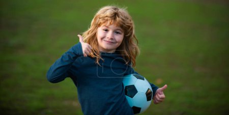 Téléchargez les photos : Soccer enfant jouer au football. Enfant tenant ballon de football, gros plan enfants portrait montrer pouces vers le haut signe de succès - en image libre de droit