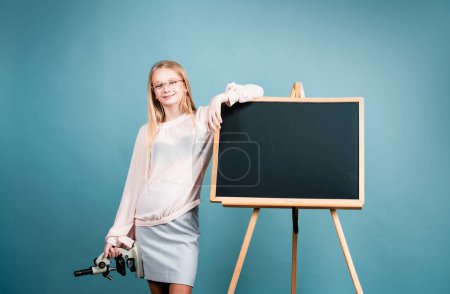 Photo for First of September. Day of knowledges. Cute blonde girl standing near blackboard wearing a school uniform. Pretty little schooler girl going to her first lesson - Royalty Free Image