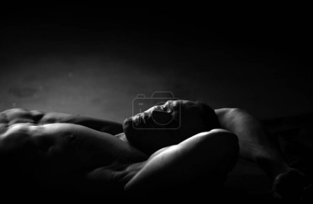 Foto de Sexy hombre musculoso desnudo con abdominales sixpack acostado en la cama. Hombre musculoso guapo relajándose - Imagen libre de derechos
