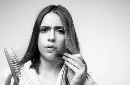 Photo for Hair loss. Woman is upset of hair loss. Portrait of sad girl with problem hair, isolated. Worried girl holding long damaged unhealthy hair in hand - Royalty Free Image
