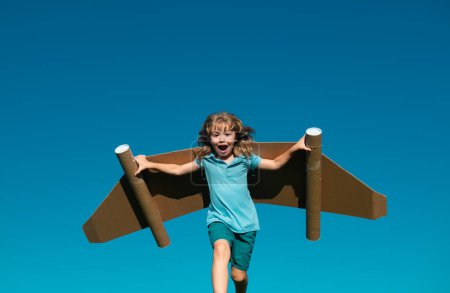 Kind mit Jet-Pack-Superheld. Kinderpilot vor sommerlichem Himmel. Junge mit Papierflieger, Spielzeugflugzeug mit Pappflügeln, Fantasie, Kinderfreiheit