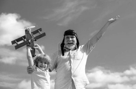 Foto de Nieto joven y viejo abuelo con avión jetpack juguete contra el cielo. Aviador piloto infantil con sueños de avión de viaje - Imagen libre de derechos