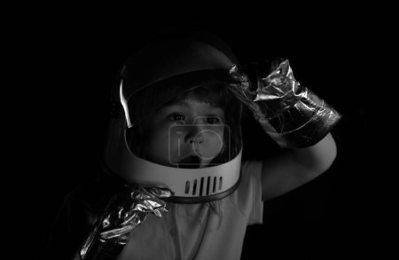 Téléchargez les photos : Un petit garçon rêve de devenir astronaute et de voler dans l'espace. Cosmos enfants en combinaison spatiale et des rêves de casque. Gros plan enfants excités visage sur la couleur néon - en image libre de droit
